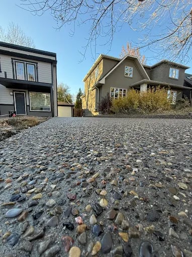 Residential neighborhood street with modern and traditional houses beside gravel driveway in spring