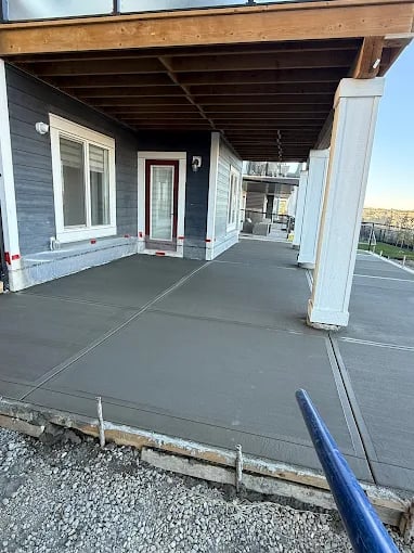 Modern house porch with wooden roof, white columns, and concrete patio floor.
