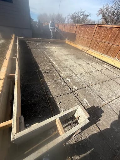 Concrete foundation or deck with wooden framing under construction in backyard